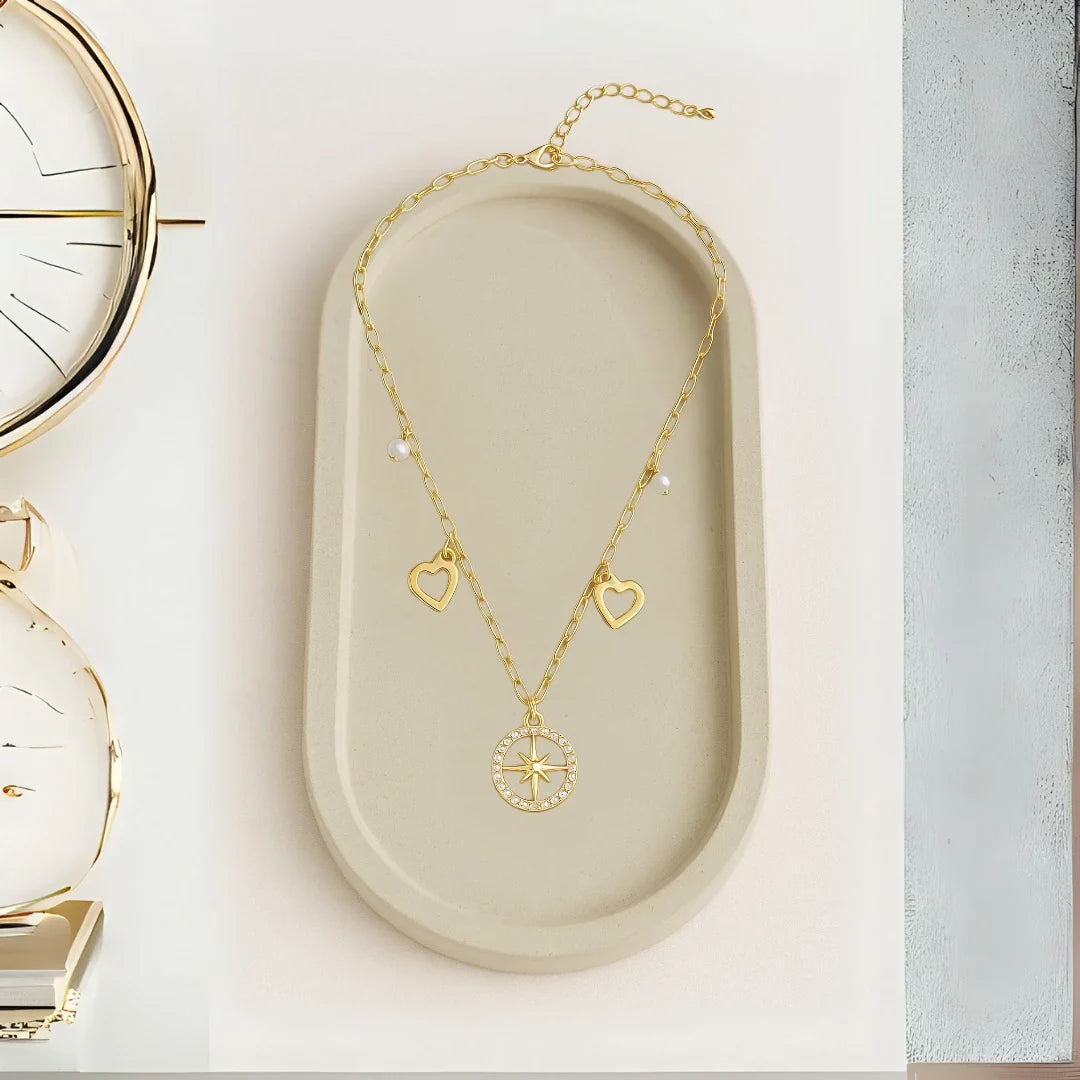Cadena con dijes de brujula cons dos perlitas y dos corazones a los lados Accesorios bañados en oro