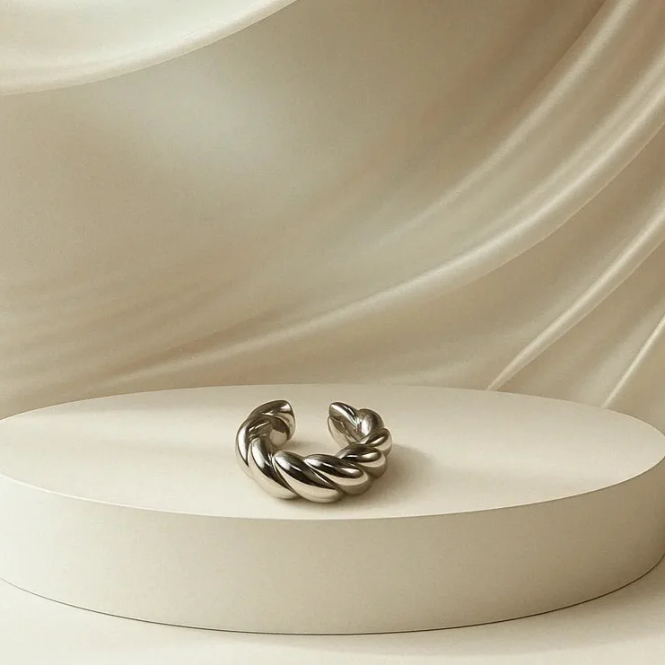 Ear cuff plaeado trenzado sobre una plataforma blanca