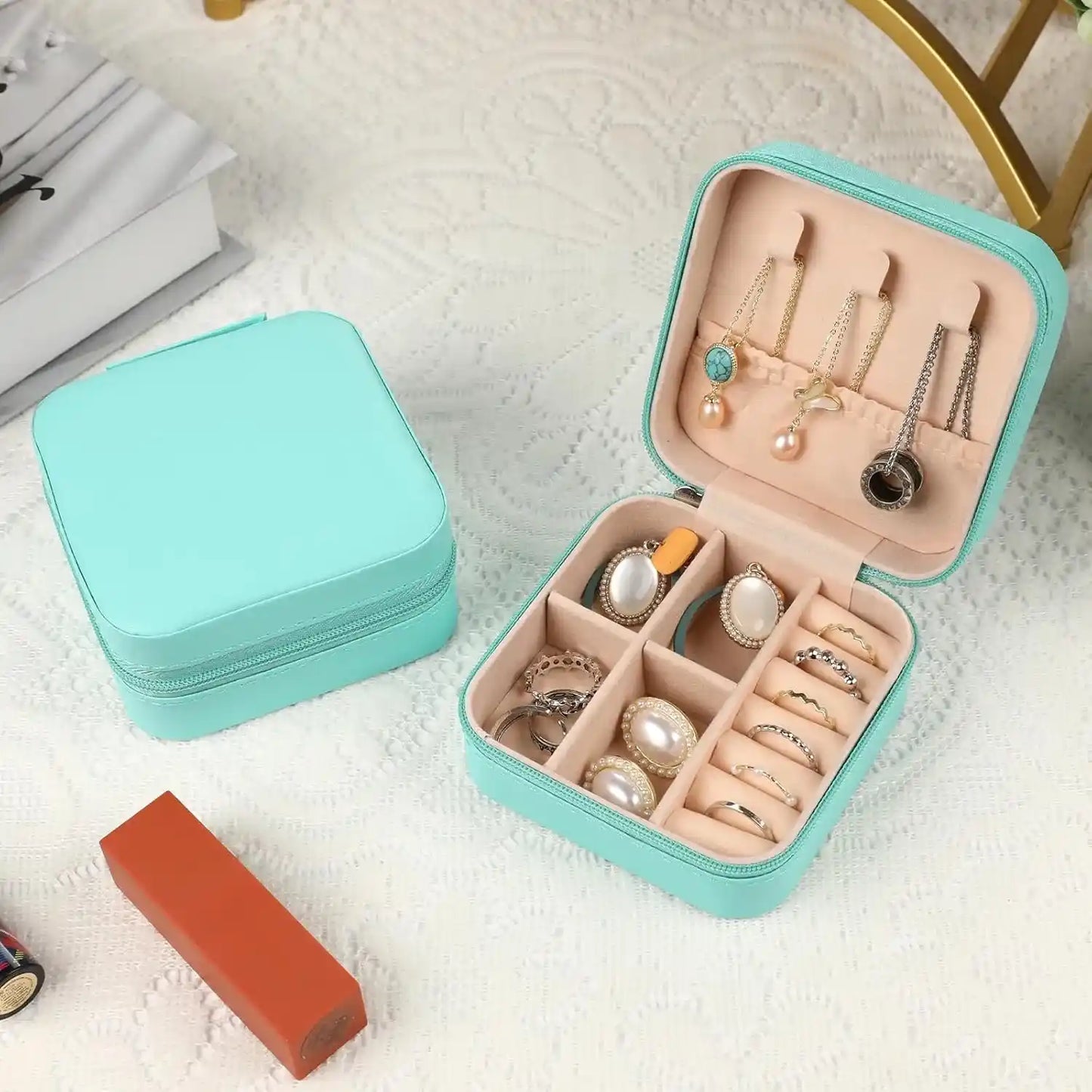 Joyero Azul Tiffany para guardar accesorios de mujer,encima de una mesa que tiene un mantel blanco y dentro contiene joyas