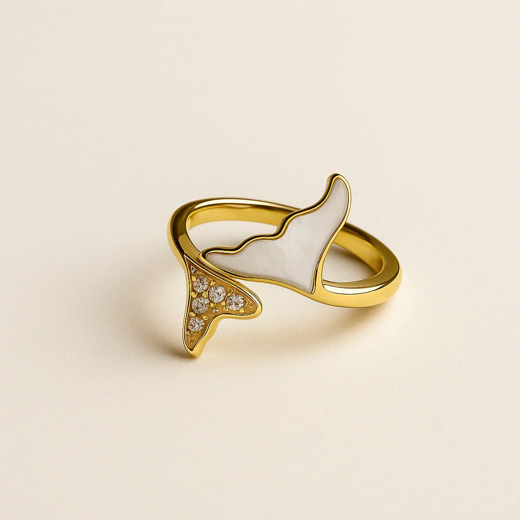 Anillo dorado con forma de cola de sirena sobre fondo claro