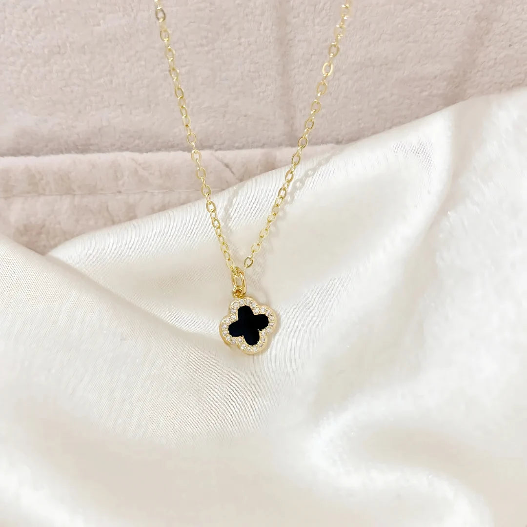 Detalle del dije trébol negro en fondo blanco satinado