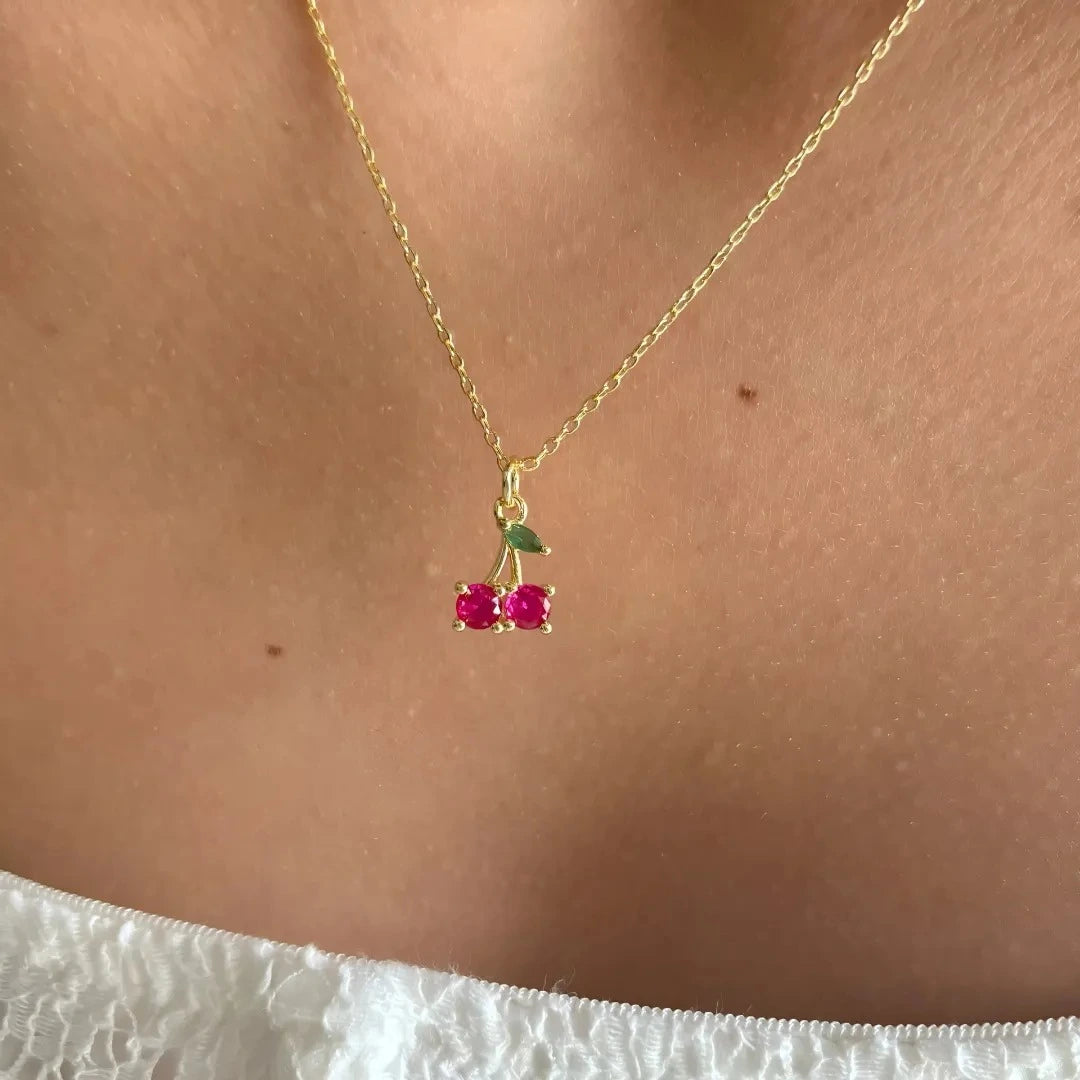Mujer usando collar con dije de cereza rosa de 1 cm
