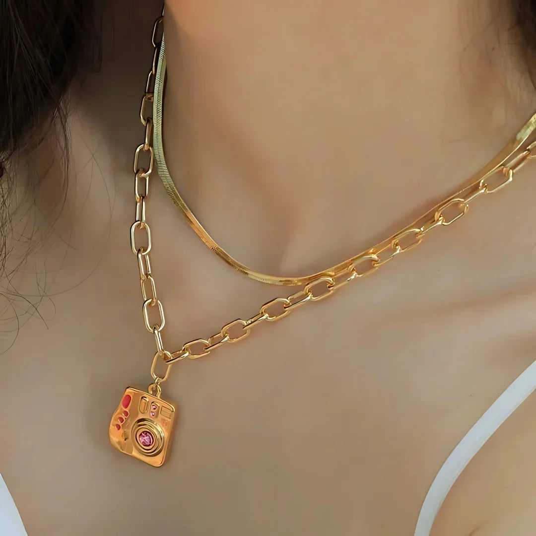 Accesorio femenino con simbolismo emotivo y diseño creativo. Joya dorada con piedra central rosa para amantes de la fotografía