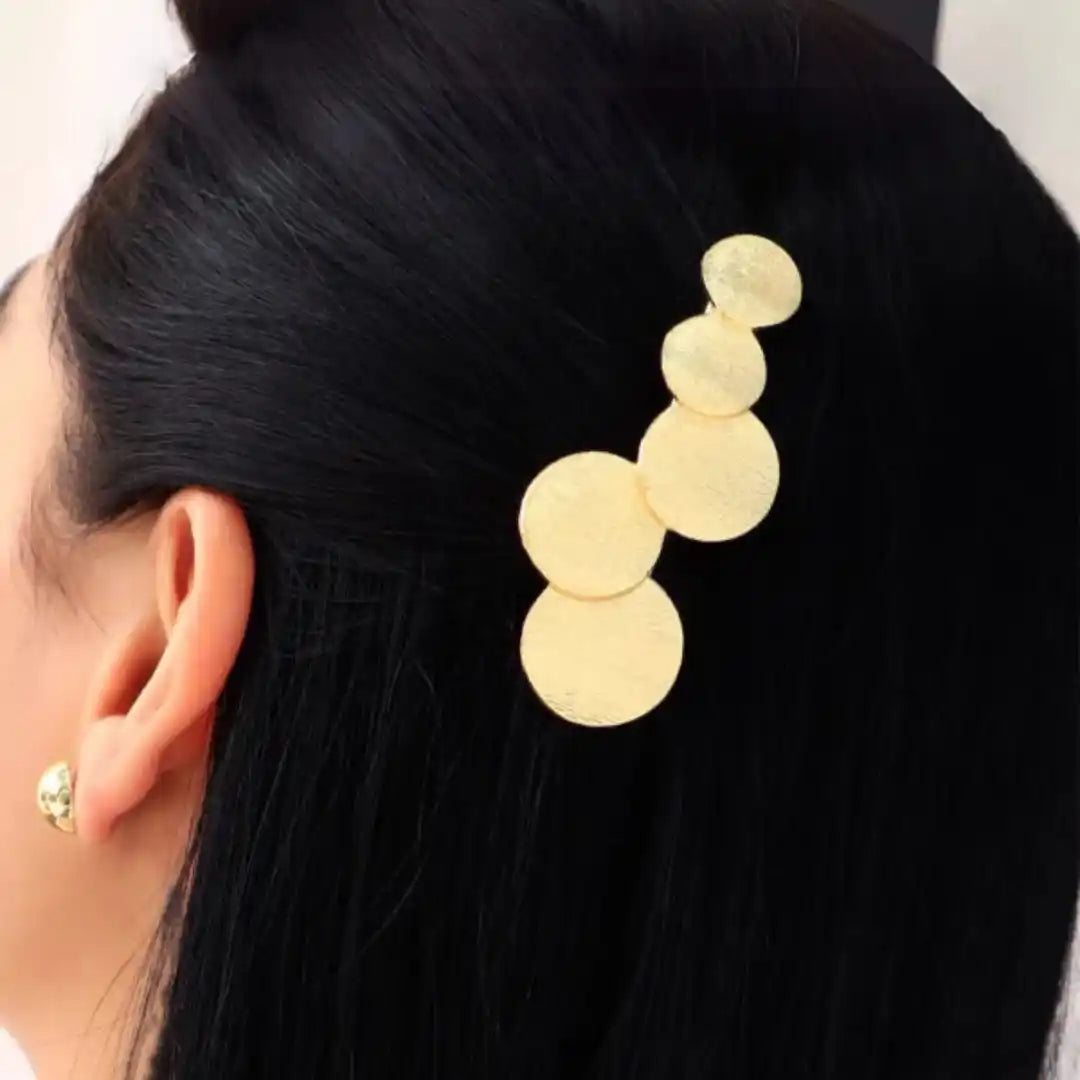 Hebilla de circulos dorados colocada en el cabello de una mujer modelo accesorios para mujer de calidad