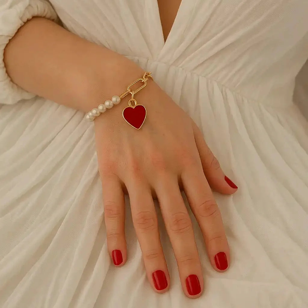 Pulsera corazón vista en la muñeca de la modelo con uñas rojas