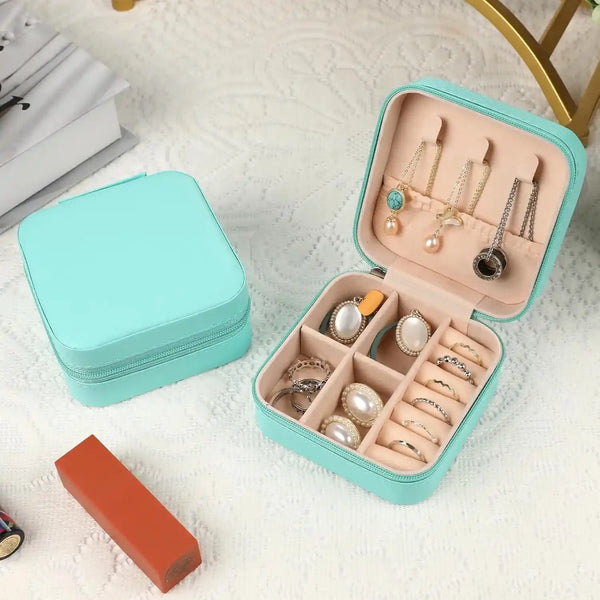 Joyero Azul Tiffany para guardar accesorios de mujer,encima de una mesa que tiene un mantel blanco y dentro contiene joyas