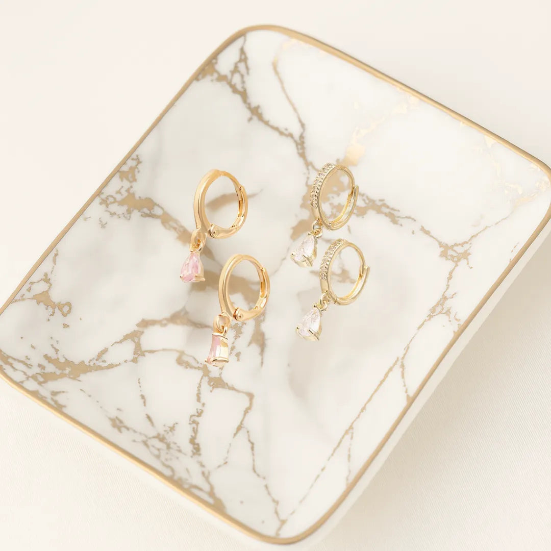 Aretes tipo huggie dorados con cristales brillantes sobre fondo claro

