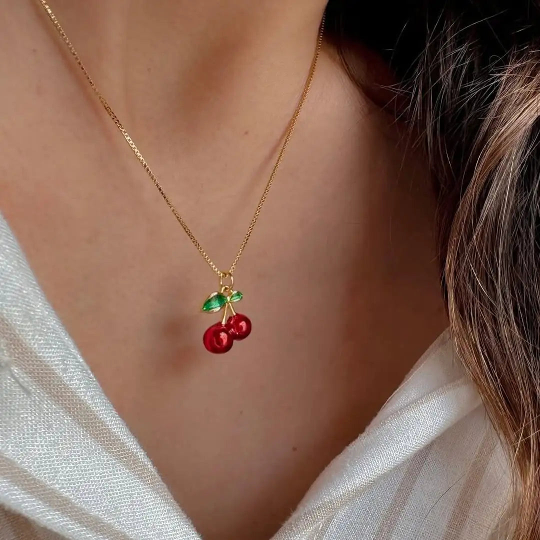 Mujer usando cadena con cereza roja en escote


