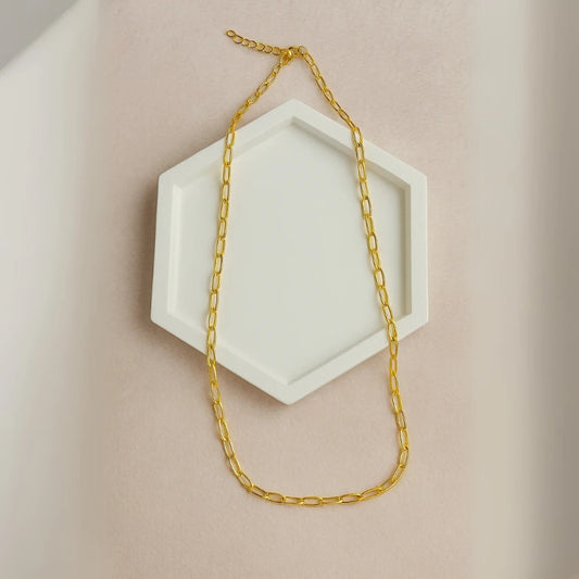 Cadena de eslabones delgados dorada con baño de oro 24K sobre base hexagonal blanca

