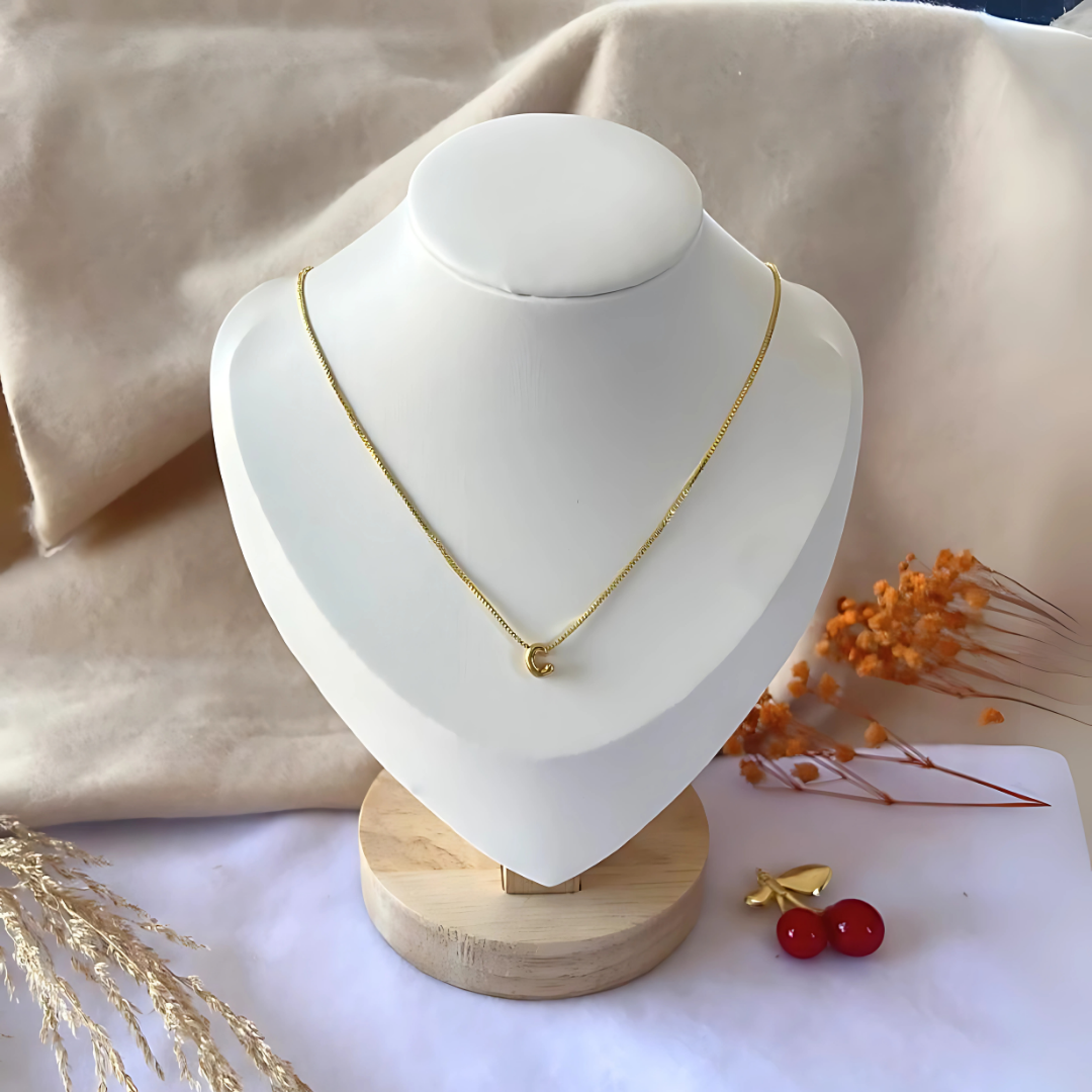 Collar con letra mini exhibido en display blanco, ideal para accesorios de mujer

