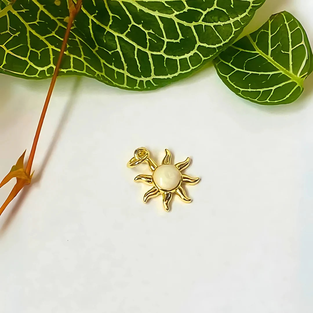 Charm en forma de sol con acabado dorado y fondo verde

