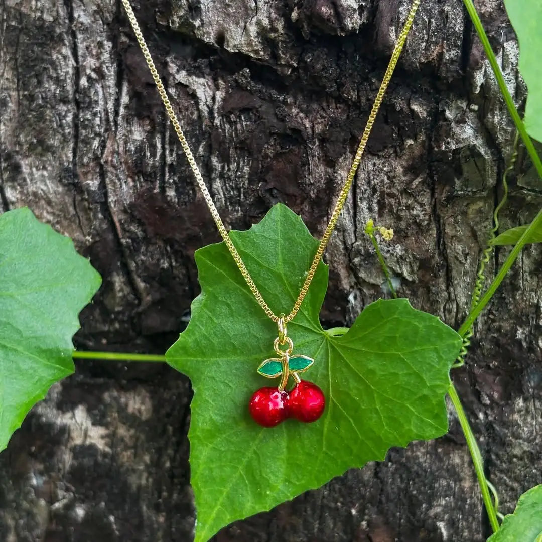 Dije de cereza sobre hojas verdes, detalle vibrante y natural

