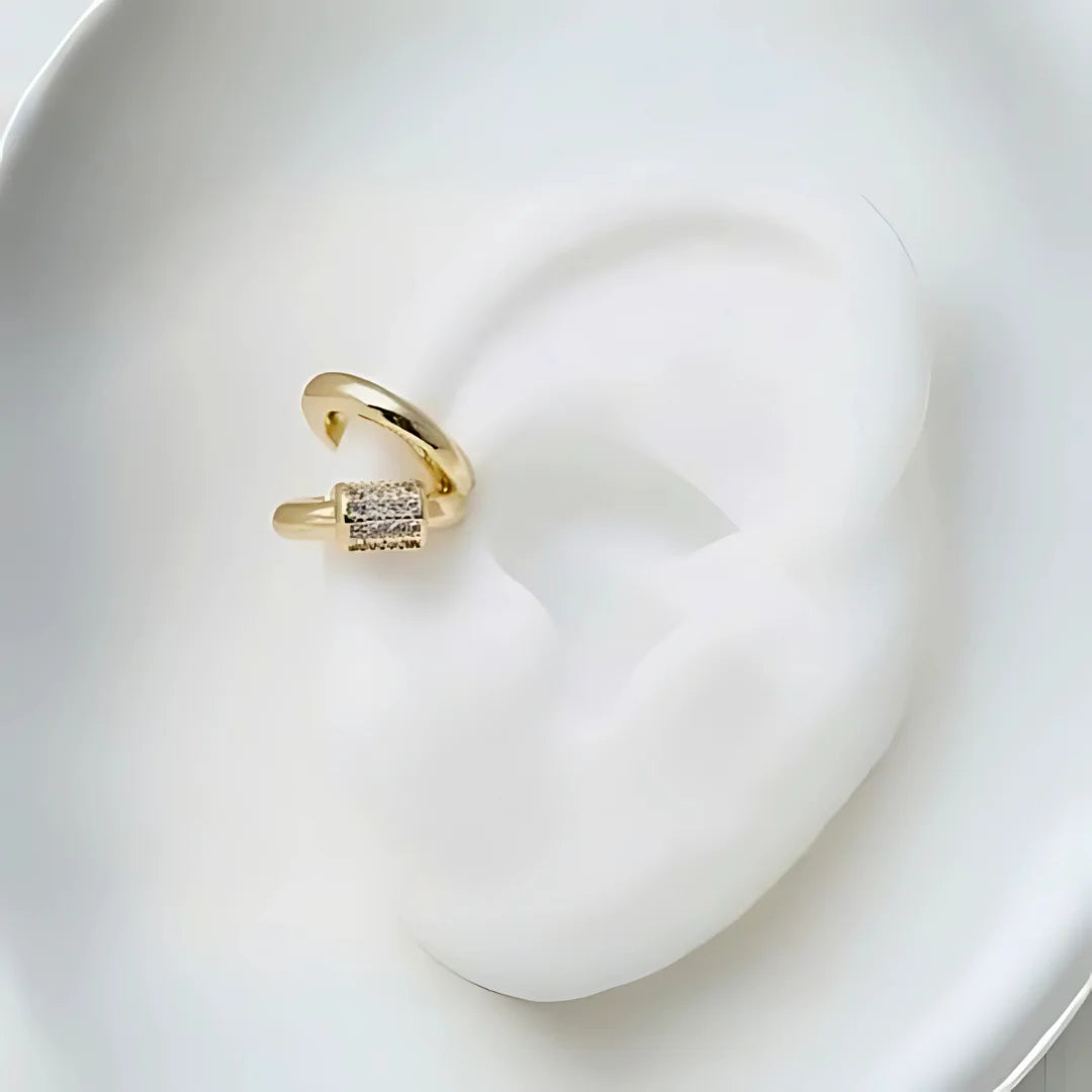 Ear cuff cilíndrico dorado con microcristales sobre fondo neutro importado