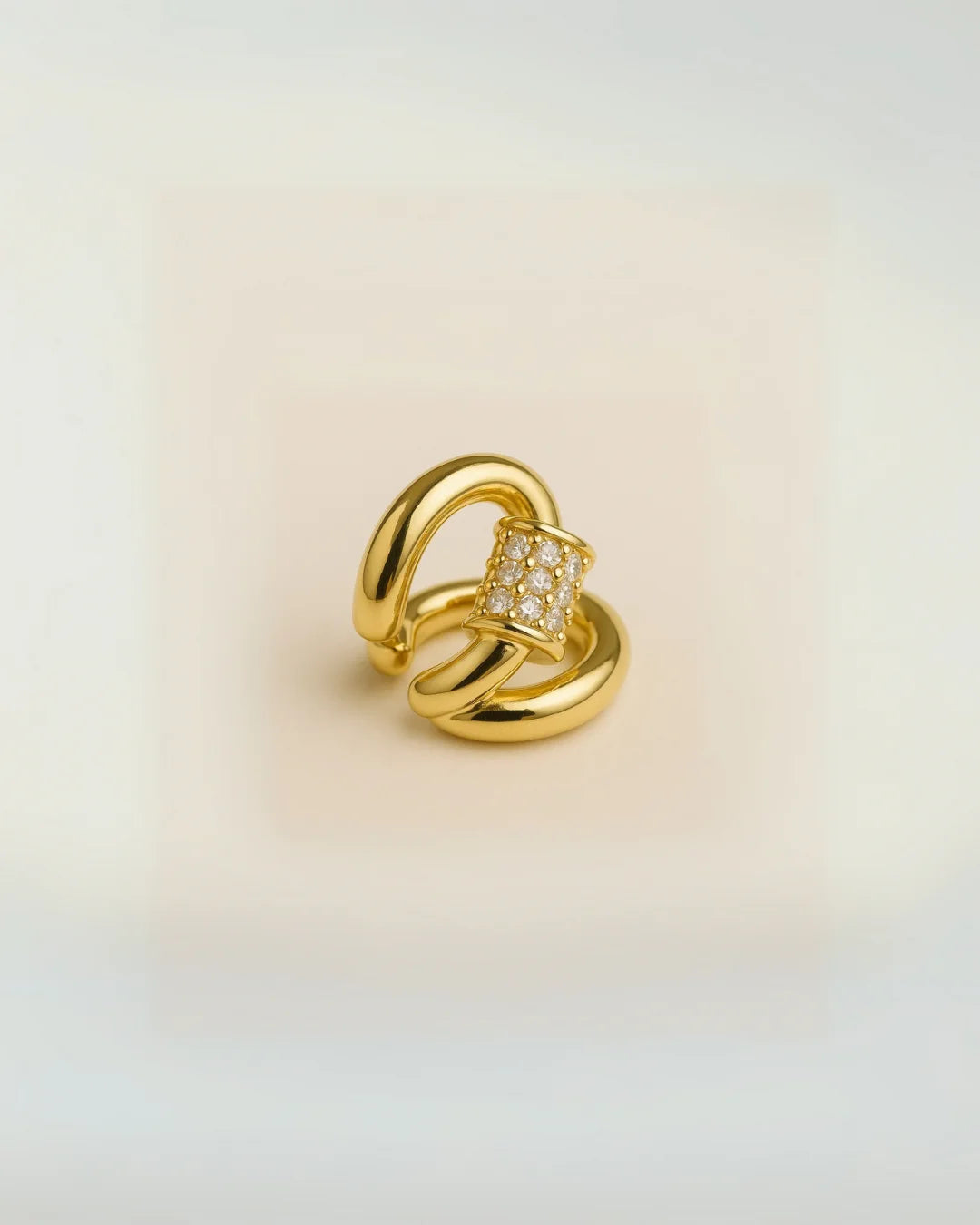 Ear cuff dorado brillante estilo moderno sobre base blanca

