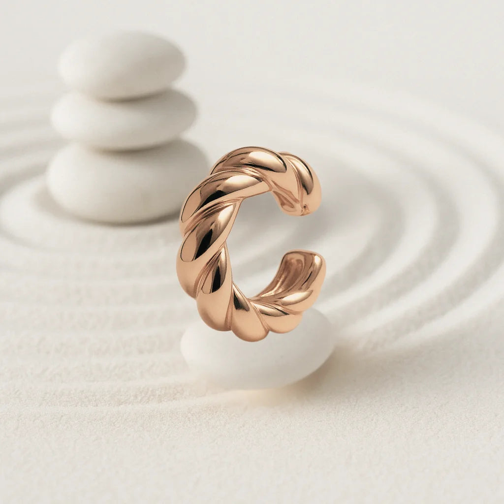 Ear cuff dorado grueso con diseño trenzado sobre fondo blanco

