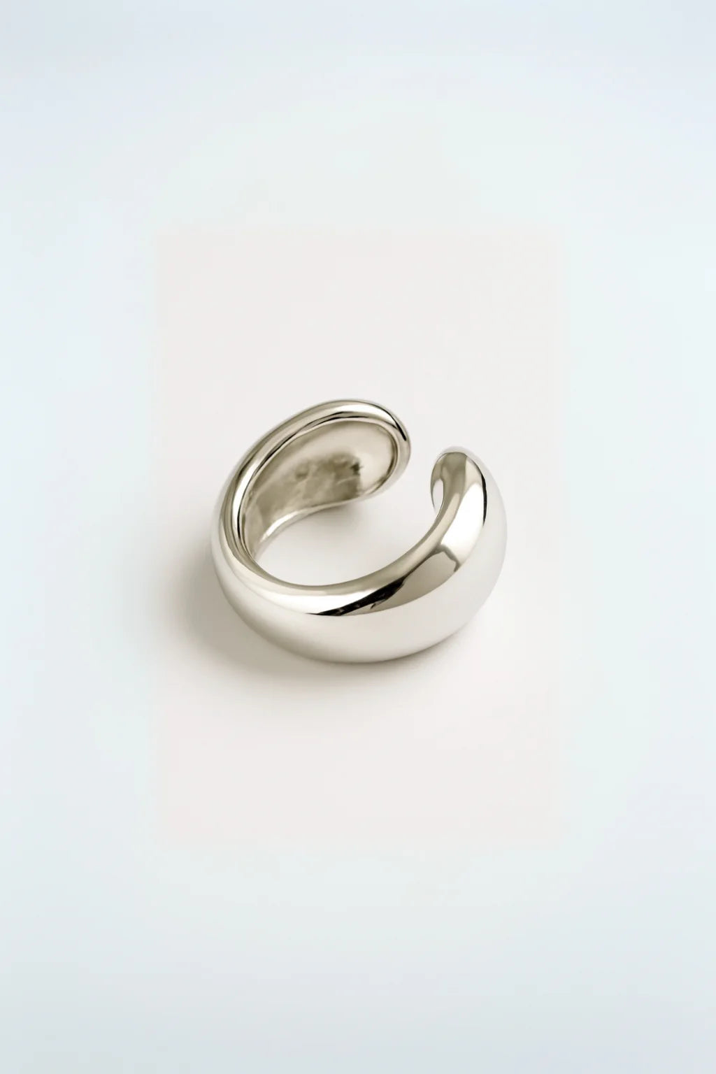 Ear cuff de diseño fluido con acabado brillante sobre fondo blanco


