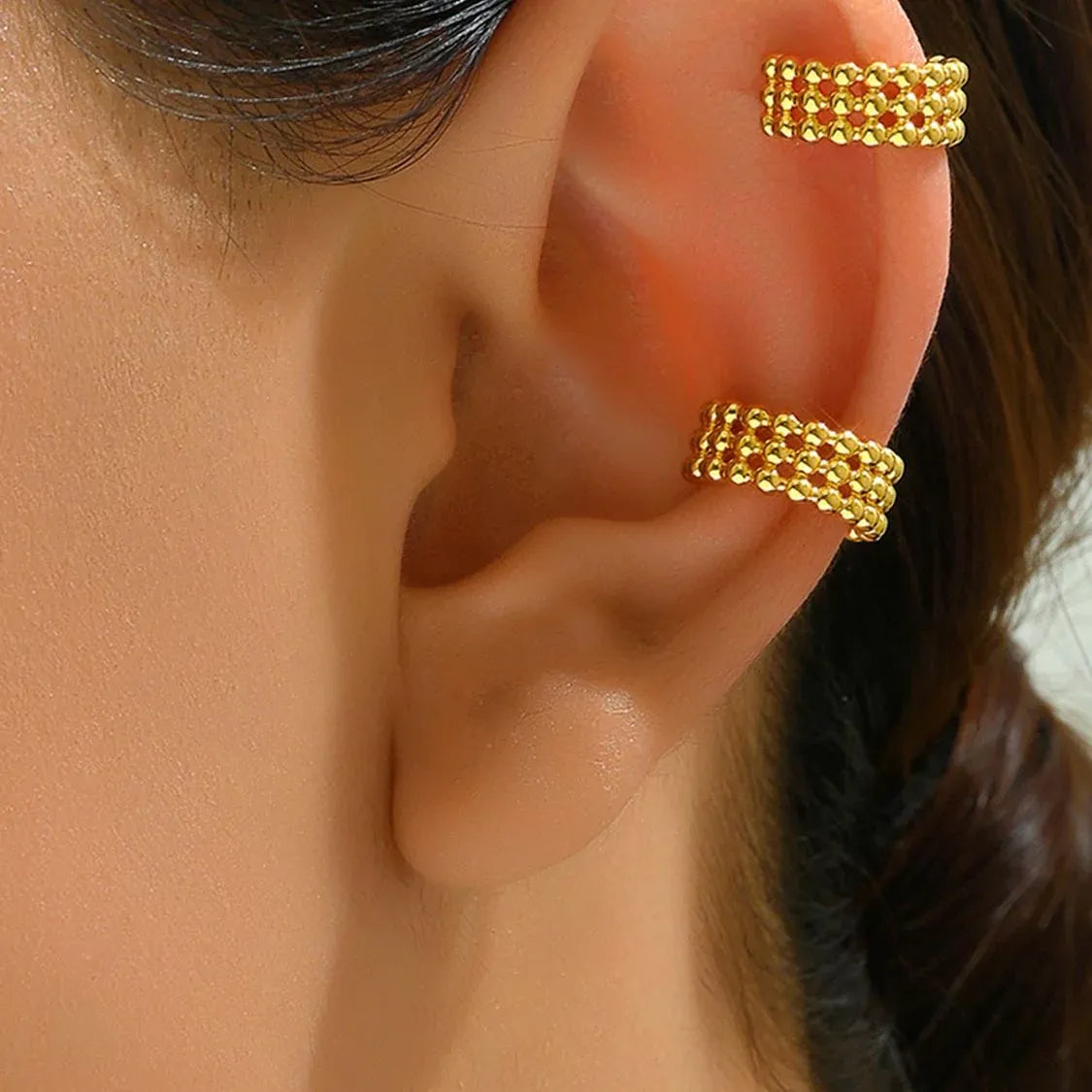 Accesorio dorado tipo ear cuff puesto en una oreja femenina

