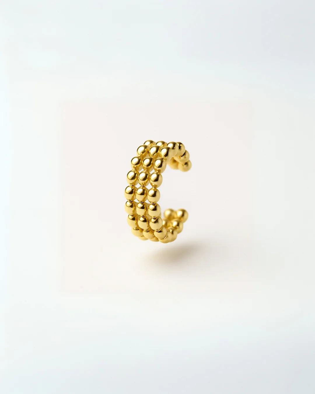 Accesorio dorado tipo ear cuff puesto en la oreja femenina

