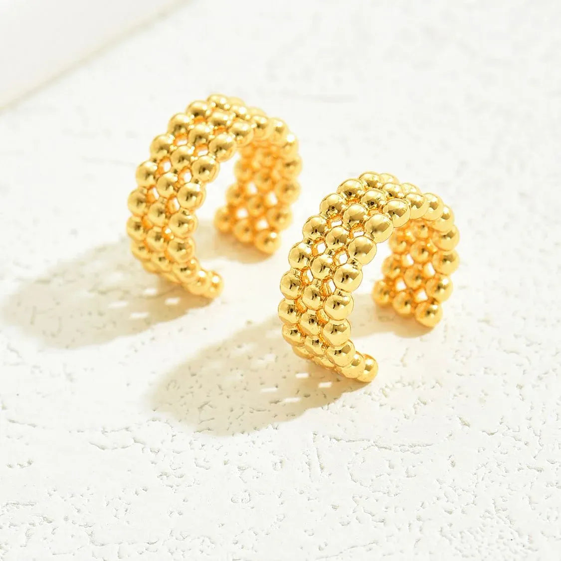 Ear cuff dorado importado con mini balines para mujer sobre fondo blanco

