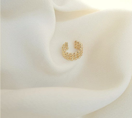 Ear cuff dorado con mini balines para mujer sobre fondo blanco

