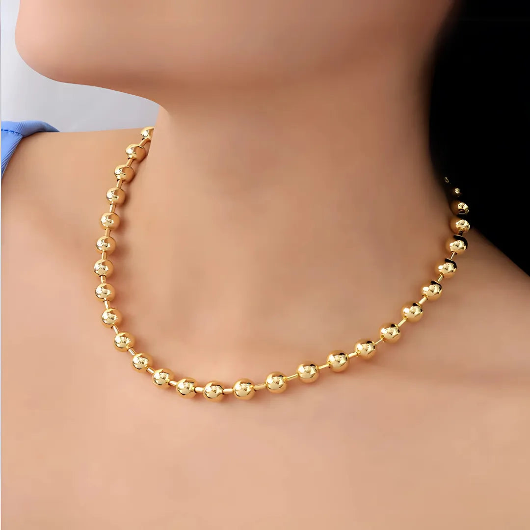 Modelo usando gargantilla de esferas medianas doradas con baño de oro 24K, accesorios para mujer sofisticados.