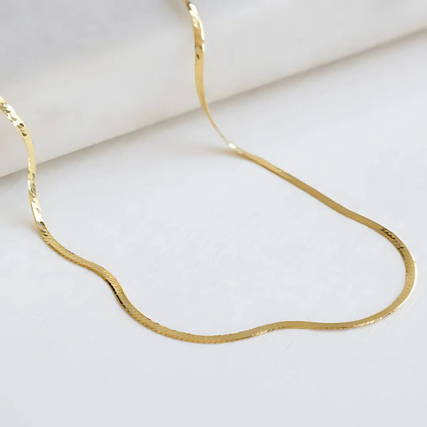 Gargantilla tejida tipo snake con baño de oro 24K, vista extendida sobre fondo blanco, accesorios para mujer de lujo.