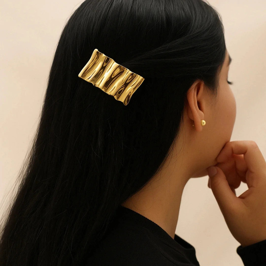 Mujer con hebilla dorada peinando cabello largo

