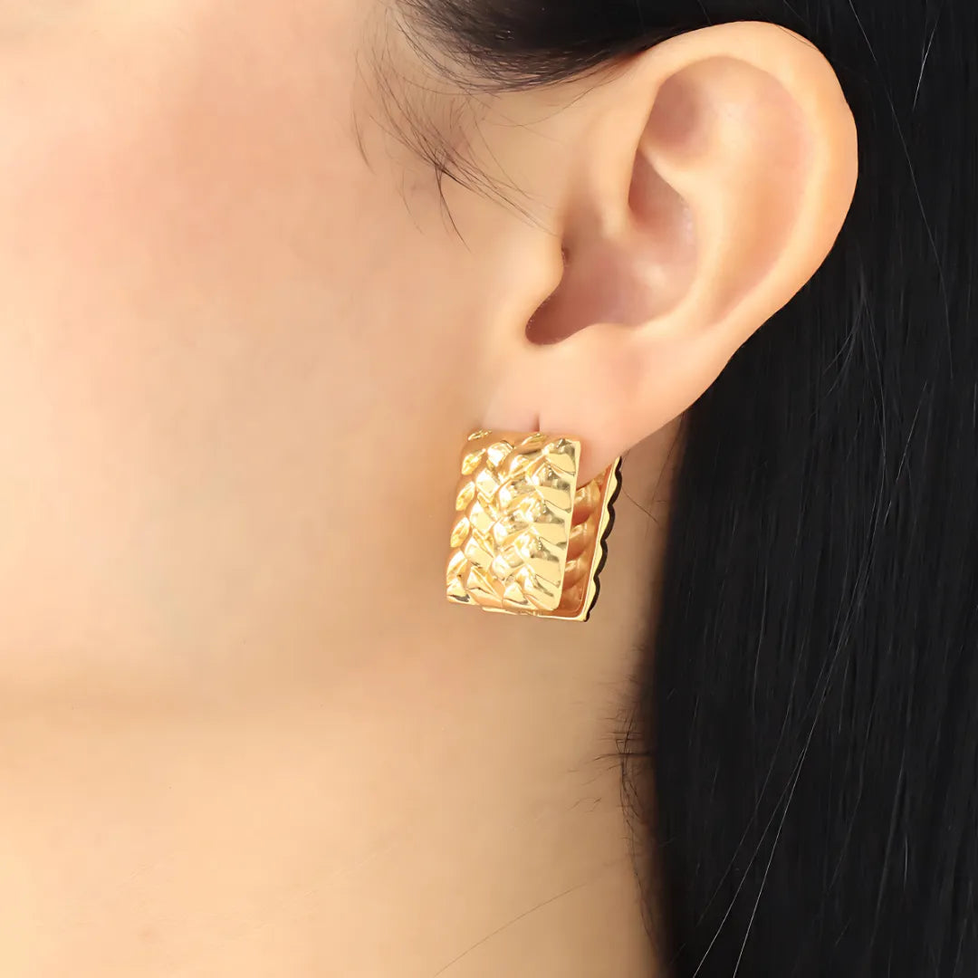 Aretes Huggies Roma en modelo, diseño cuadrado con acabado dorado ideal como accesorios para mujer modernos.