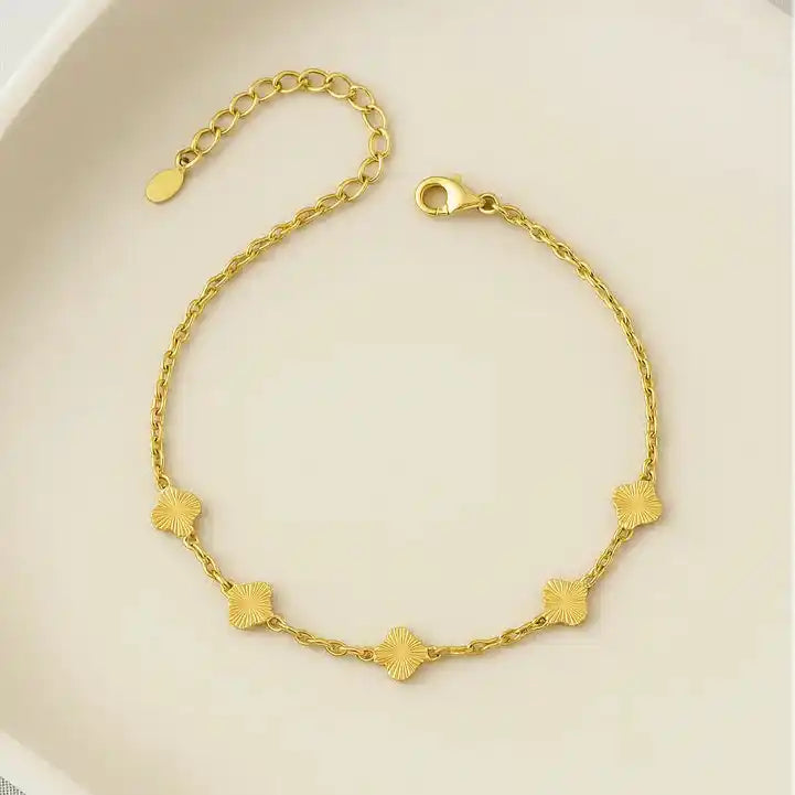 tobillera dorada enchapada en oro 24k apliques trebol sobre una superficie color beige
