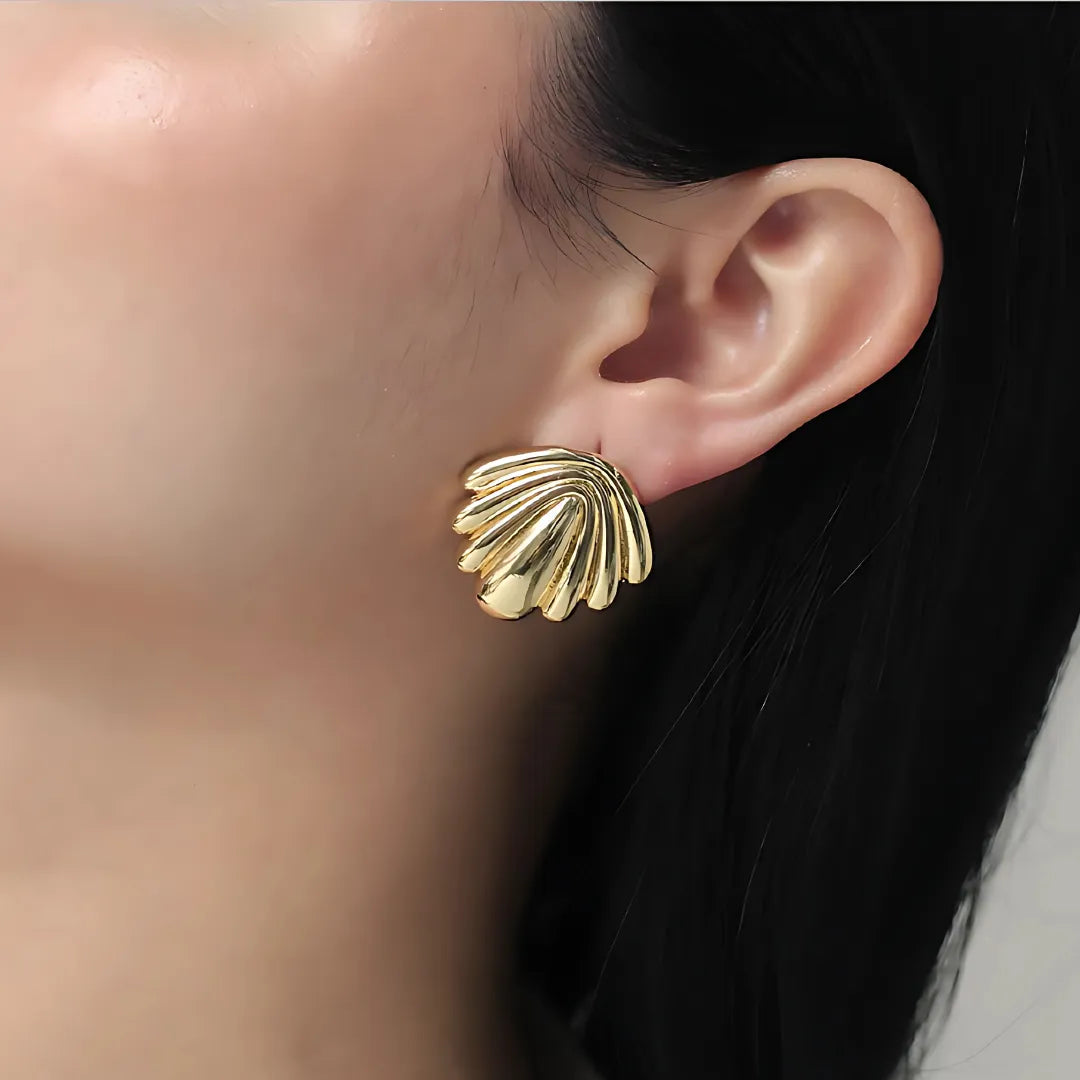 Modelo usando aretes grandes dorados de inspiración marina hechos en Colombia

