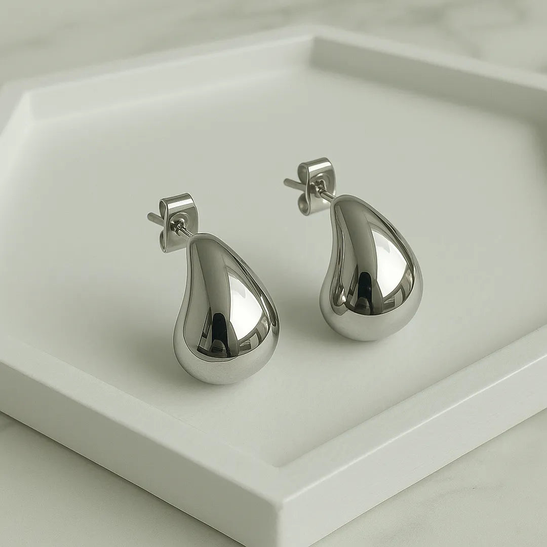 Aretes rodinados sobre base blanca con forma curva

