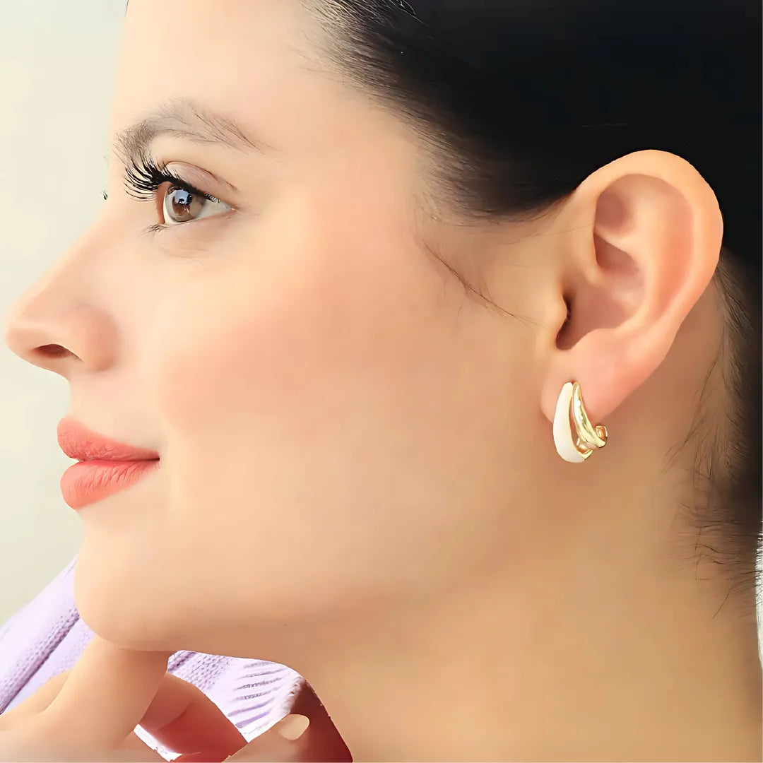 Modelo usando aretes dorados con diseño colombiano y perla nácar

